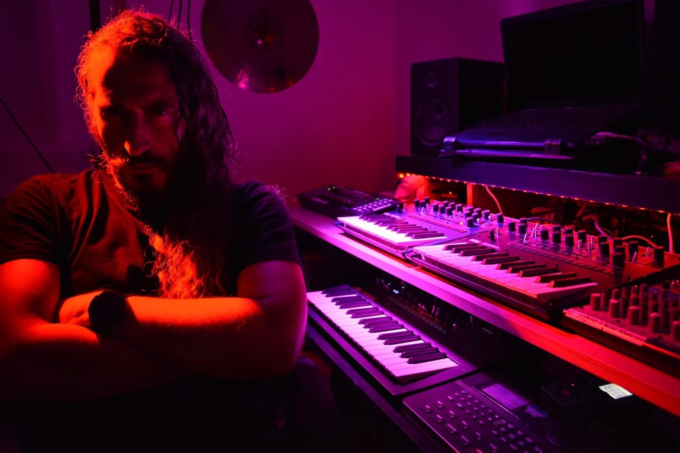Antony Coia i sin studio, omgiven av synthar i rött ljus